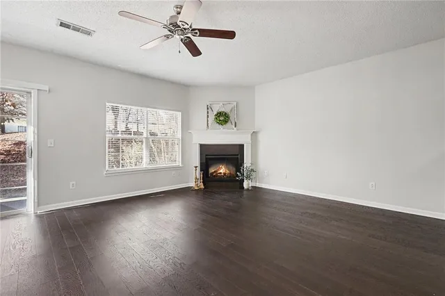 a view of empty room with wooden floor fireplace and windows
