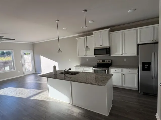 a kitchen with stainless steel appliances granite countertop a sink a stove a microwave and cabinets