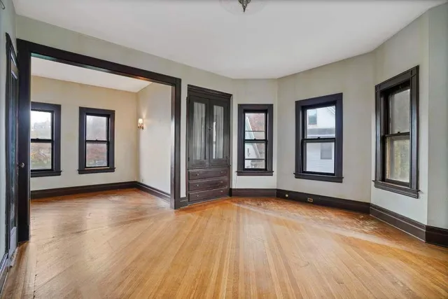 an empty room with wooden floor and windows
