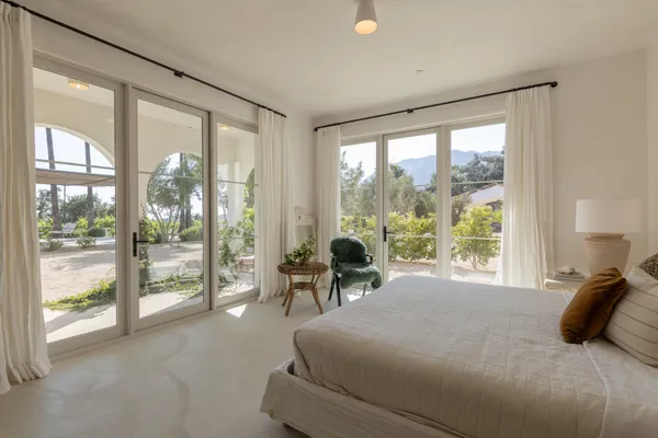 a bedroom with a bed and large windows