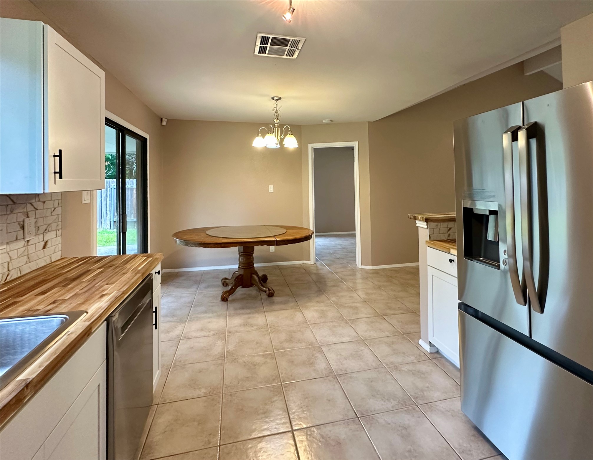 709 Brookside Pass Cedar Park, TX 78613 - Photo 5 of 10 The kitchen and dining area feature light-toned tiled flooring, white cabinetry with dark hardware, butcher block countertops, and a stainless steel refrigerator