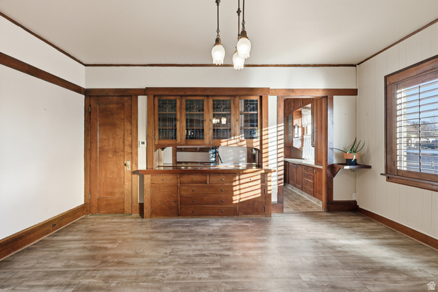 202 Main Street Smithfield, UT 84335 - Photo 6 of 32 Bar with decorative light fixtures, wood finished floors, ornamental molding, brown cabinets, and glass insert cabinets