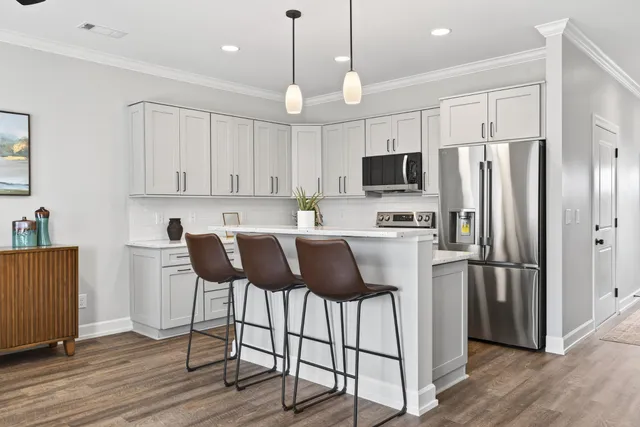 a kitchen with stainless steel appliances granite countertop a refrigerator a stove a sink and chairs with wooden floor