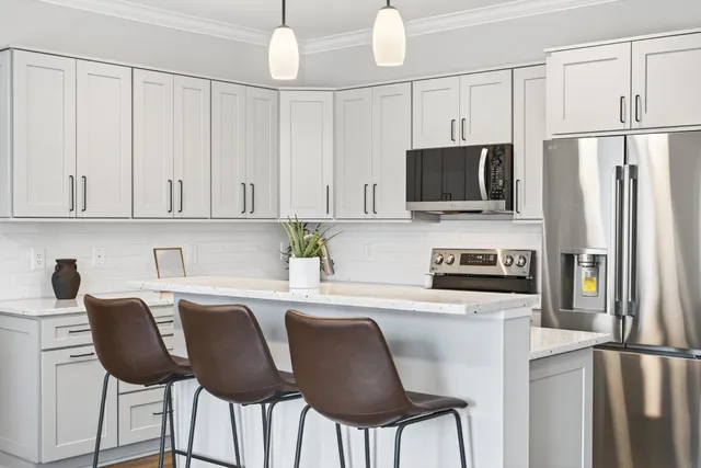 a kitchen with stainless steel appliances granite countertop a refrigerator a stove a sink dishwasher and white cabinets with wooden floor