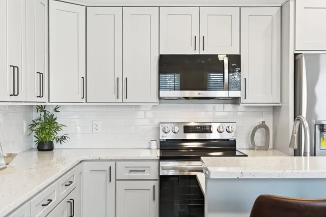 a kitchen with stainless steel appliances granite countertop white cabinets a stove top oven a sink and dishwasher