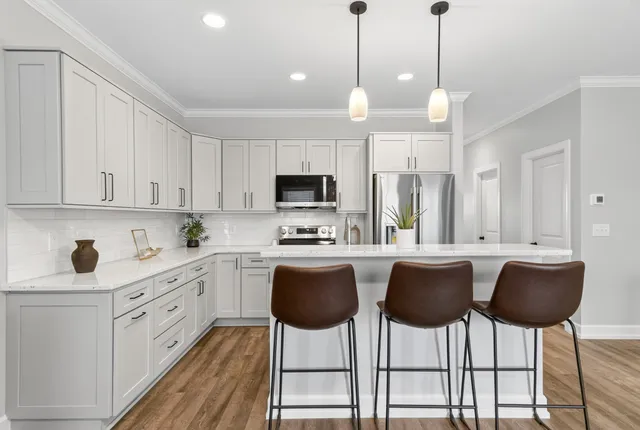 a kitchen with stainless steel appliances a table chairs refrigerator and cabinets