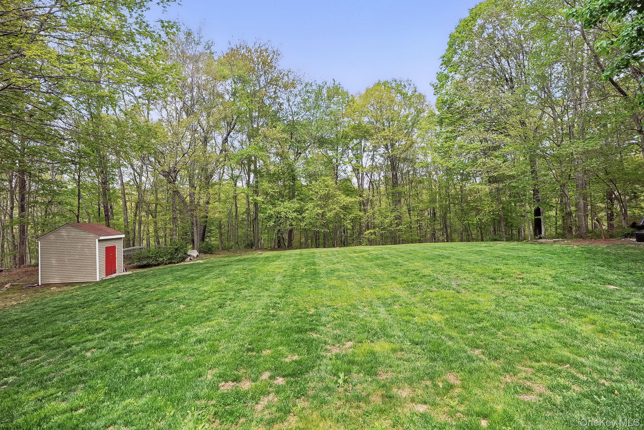 304 Church Road Putnam Valley, NY 10579 - Photo 41 of 50 View of grassy yard with a storage unit, an outdoor structure, and a view of trees