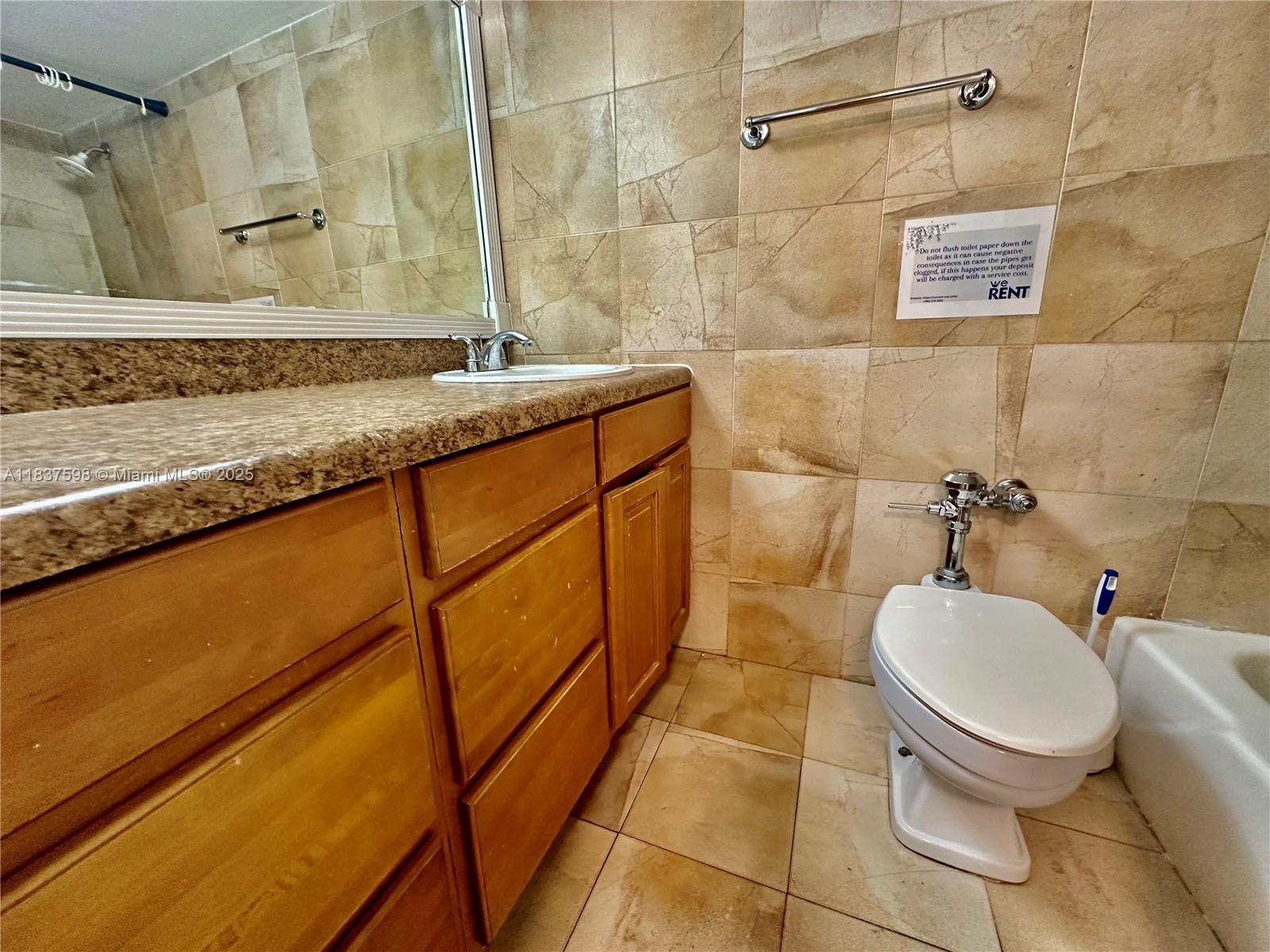 26 Diplomat Parkway, Unit 2368 Hallandale Beach, FL 33009 - Photo 5 of 12 a bathroom with a granite countertop sink toilet and a mirror
