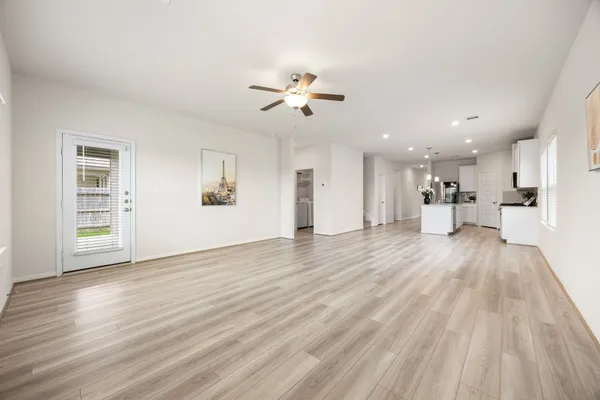 an empty room with wooden floor ceiling fan and windows