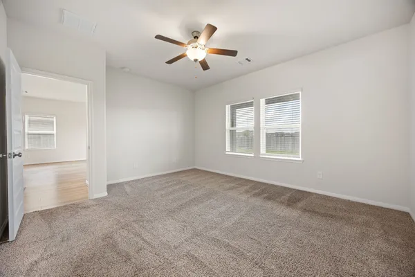 an empty room with windows and ceiling fan