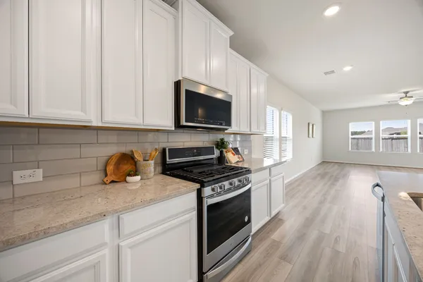 a kitchen with stainless steel appliances granite countertop a stove a sink and a microwave