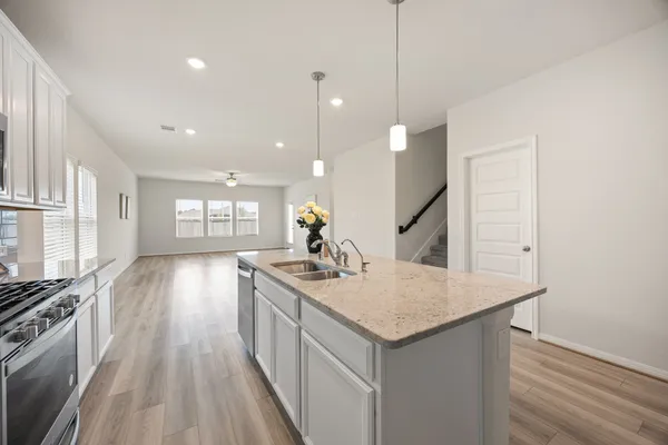 a kitchen with a sink stove and wooden floor