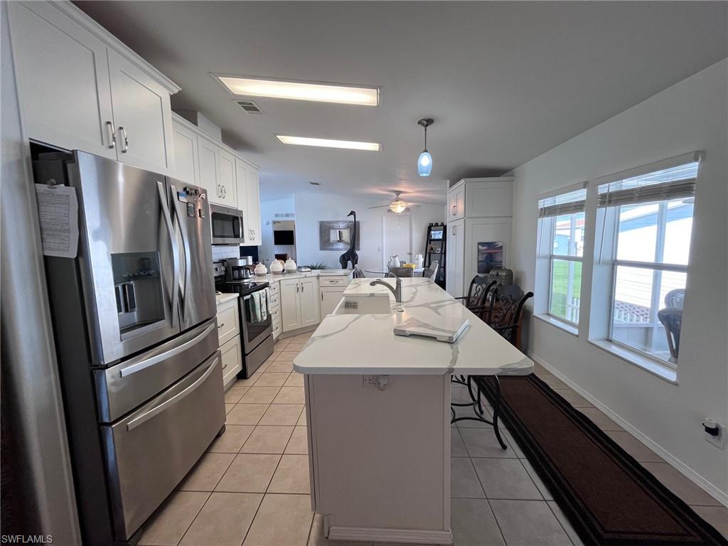 a kitchen with stainless steel appliances kitchen island granite countertop a refrigerator and a sink