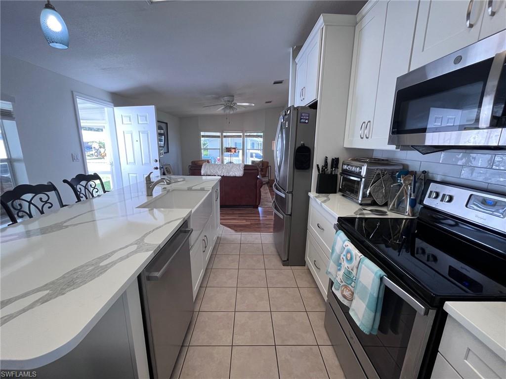 65 Turquoise Avenue, Unit 65T Naples, FL 34114 - Photo 4 of 34 a kitchen with stainless steel appliances granite countertop a stove a sink and a microwave