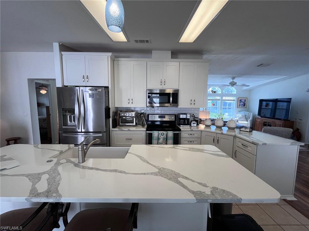 65 Turquoise Avenue, Unit 65T Naples, FL 34114 - Photo 5 of 34 a kitchen with stainless steel appliances a stove a sink a microwave a refrigerator a dining table and chairs