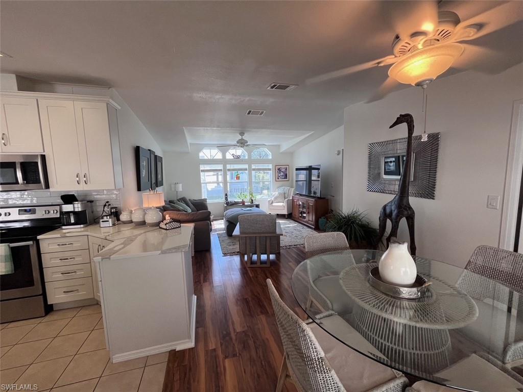 65 Turquoise Avenue, Unit 65T Naples, FL 34114 - Photo 9 of 34 a living room with furniture a chandelier and kitchen view