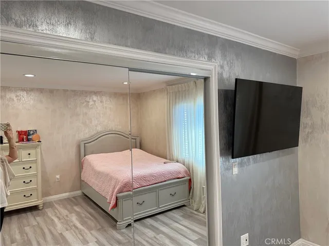 a bedroom with a bed and a flat tv screen on dresser