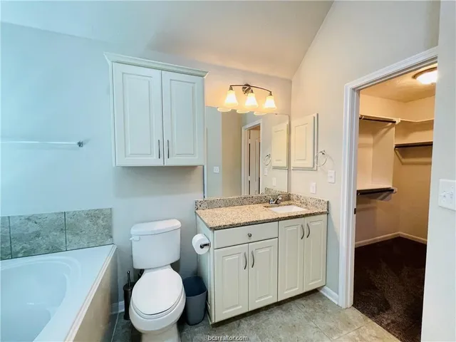 a bathroom with a granite countertop toilet sink and mirror