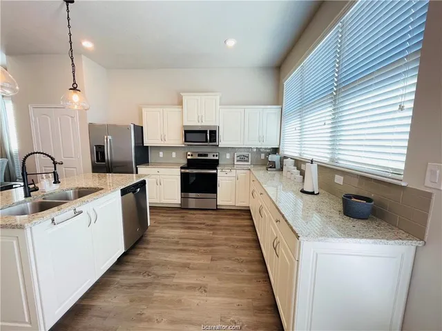 a large kitchen with stainless steel appliances granite countertop a sink and stove