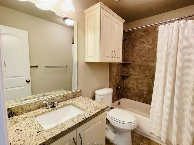 a bathroom with a granite countertop sink toilet and shower