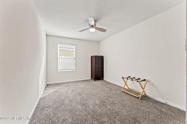 an empty room with windows and ceiling fan