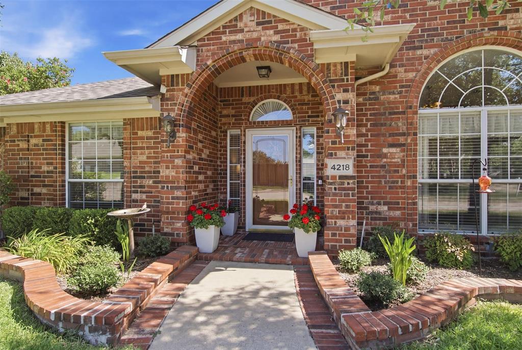 4218 Glistening Spring Rowlett, TX 75088 - Photo 1 of 39 Brick exterior featuring an arched entryway, transom window above the door, and decorative outdoor lighting