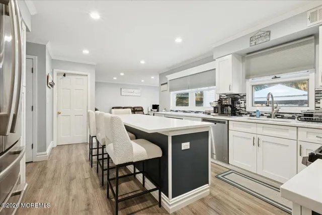 a kitchen with stainless steel appliances granite countertop a table chairs sink and cabinets