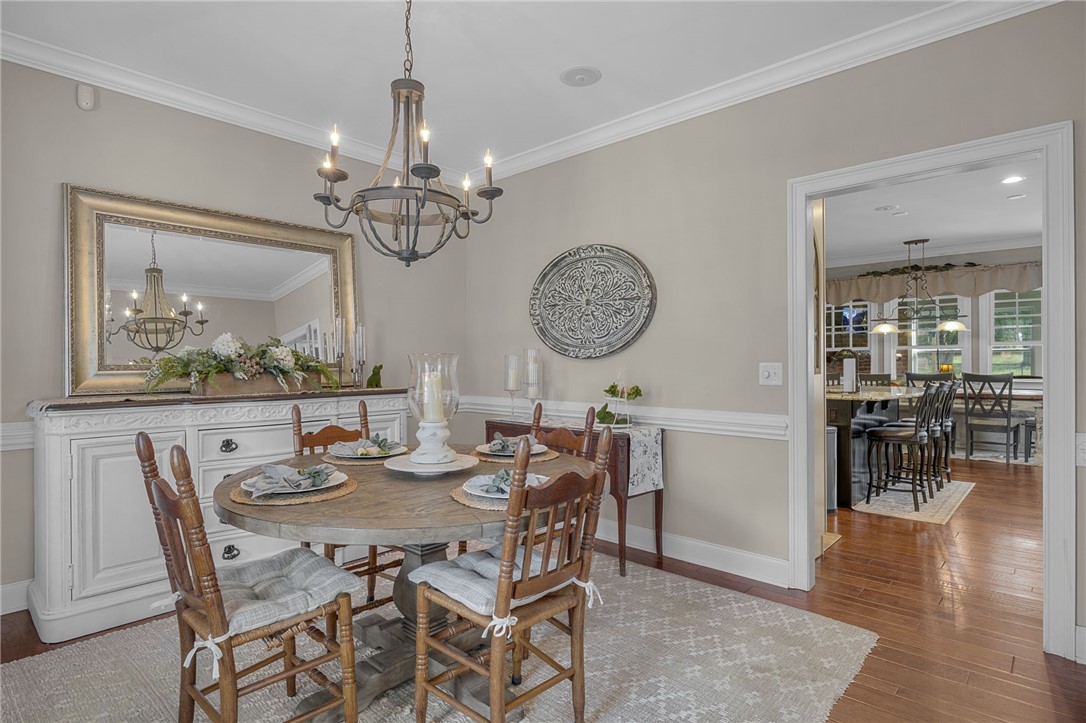 233 Bowen Drive Anderson, SC 29621 - Photo 6 of 50 Elegant dining space featuring a chandelier and rich hardwood flooring, seamlessly connecting to the kitchen.