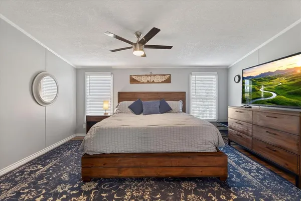 a bedroom with a bed and a flat tv screen on dresser