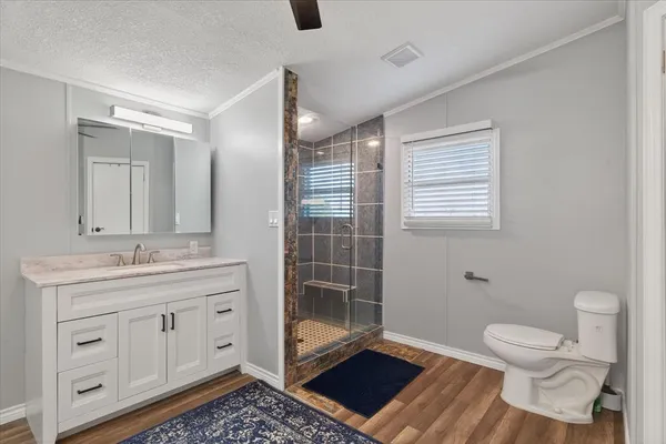 a bathroom with a granite countertop toilet a sink a mirror and vanity