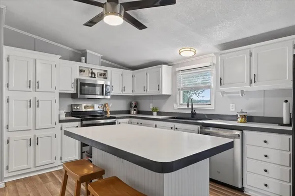 a kitchen with stainless steel appliances a sink a stove a refrigerator cabinets and a window