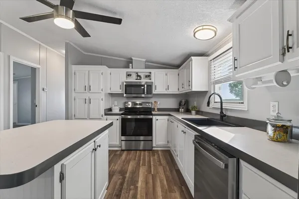 a kitchen with kitchen island granite countertop a sink appliances cabinets and furniture