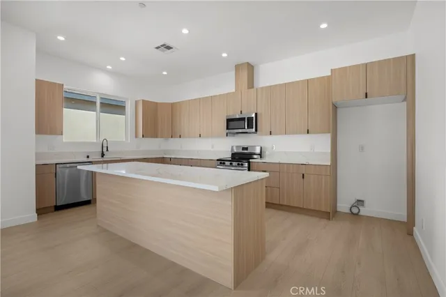 a kitchen with kitchen island granite countertop a sink stainless steel appliances and cabinets