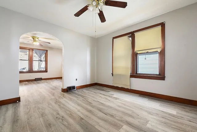 a view of an empty room with a window and wooden floor