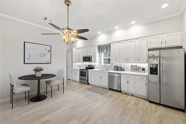 a large kitchen with stainless steel appliances a sink dishwasher a stove and a refrigerator with wooden floor