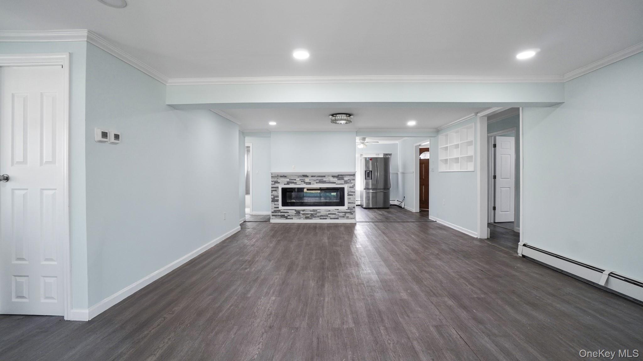 63 Blacksmith Road Levittown, NY 11756 - Photo 12 of 25 Open concept room featuring wood-finish flooring, recessed lighting, and a modern fireplace with a stacked stone surround