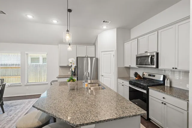 a kitchen with stainless steel appliances granite countertop a sink stove and refrigerator