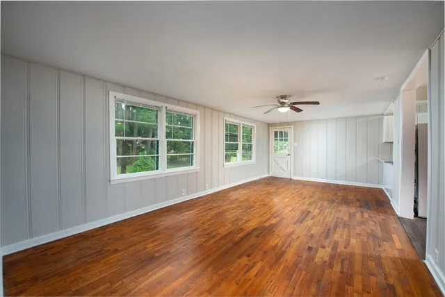 a view of empty room with wooden floor and fan