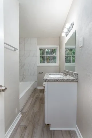 a bathroom with a granite countertop sink and a bathtub