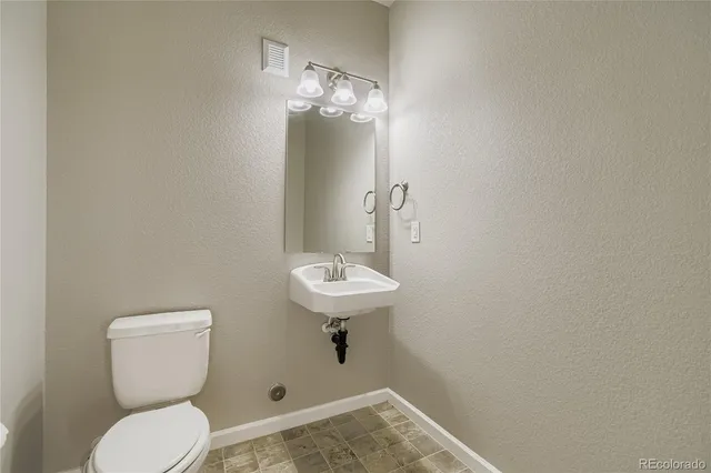 a bathroom with a toilet a sink and mirror