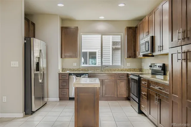 a kitchen with stainless steel appliances granite countertop a refrigerator stove and sink