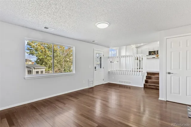 a view of an empty room with a window and wooden floor