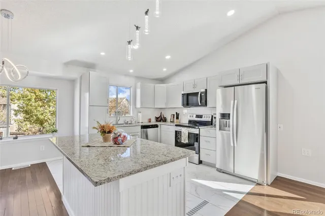 a kitchen with stainless steel appliances granite countertop a sink refrigerator and cabinets