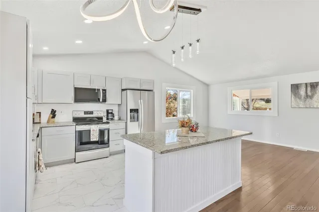 a kitchen with stainless steel appliances granite countertop a sink a stove a refrigerator cabinets and living room view