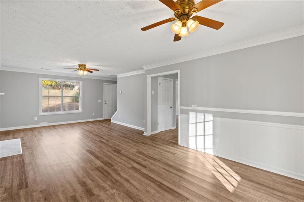 418 Ellerbe Drive Statham, GA 30666 - Photo 9 of 24 an empty room with wooden floor chandelier fan and windows