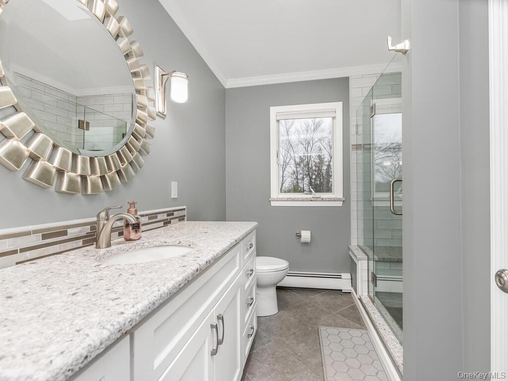 70 Breckenridge Road Mahopac, NY 10541 - Photo 14 of 29 Full bathroom featuring vanity, a stall shower, a baseboard heating unit, light tile patterned flooring, and crown molding