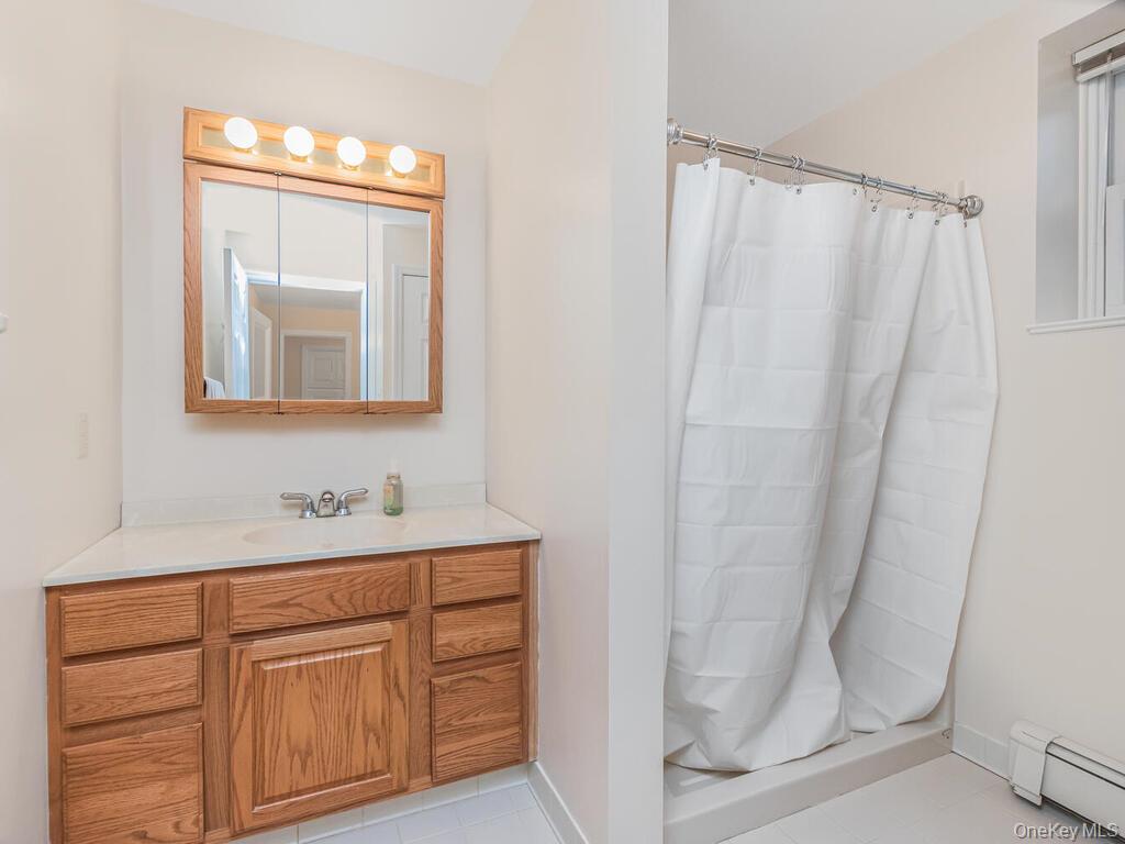 70 Breckenridge Road Mahopac, NY 10541 - Photo 16 of 29 Full bath featuring a baseboard heating unit, a stall shower, vanity, and light tile patterned floors
