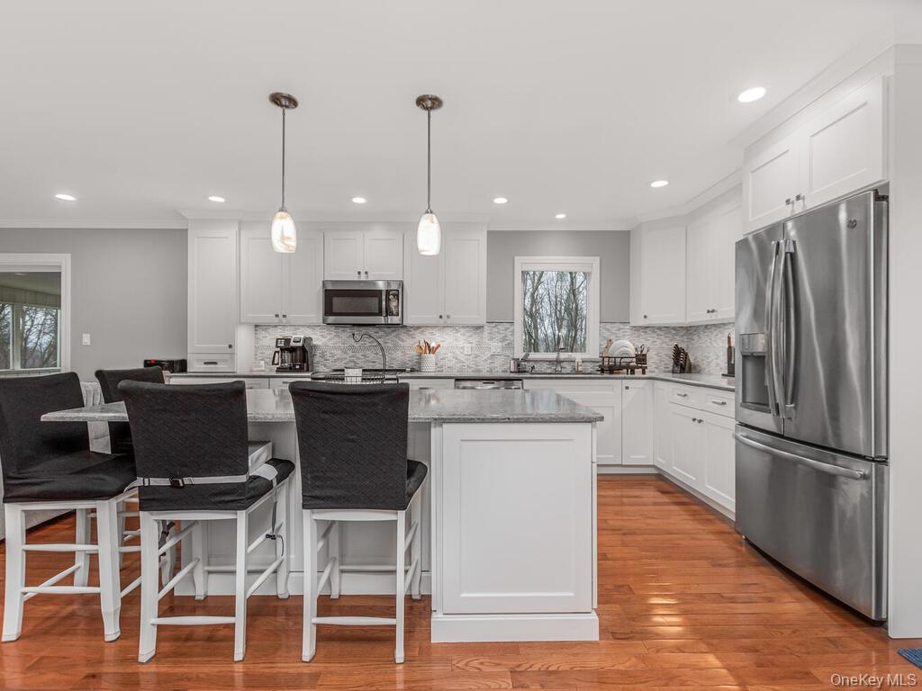 70 Breckenridge Road Mahopac, NY 10541 - Photo 3 of 29 Kitchen with stainless steel appliances, light stone countertops, white cabinetry, hanging light fixtures, and a breakfast bar