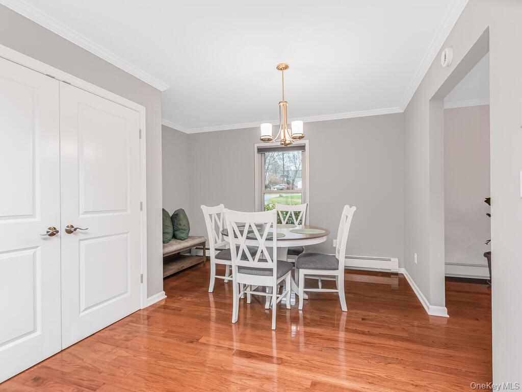70 Breckenridge Road Mahopac, NY 10541 - Photo 5 of 29 Dining area with light wood-style flooring, a chandelier, a baseboard radiator, and crown molding