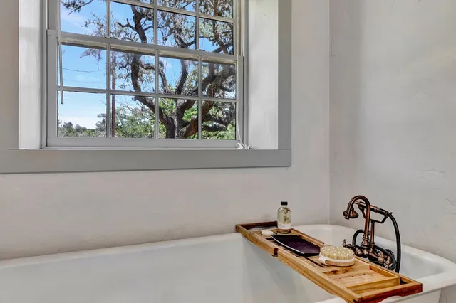 a bathroom with a tub a sink and a large window